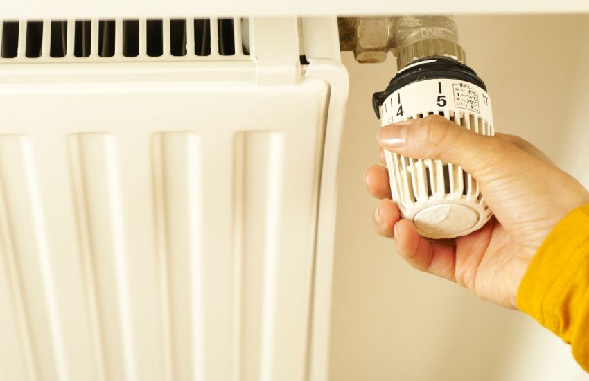 homeowner checking a furnace thermostat panel in a basement utility room